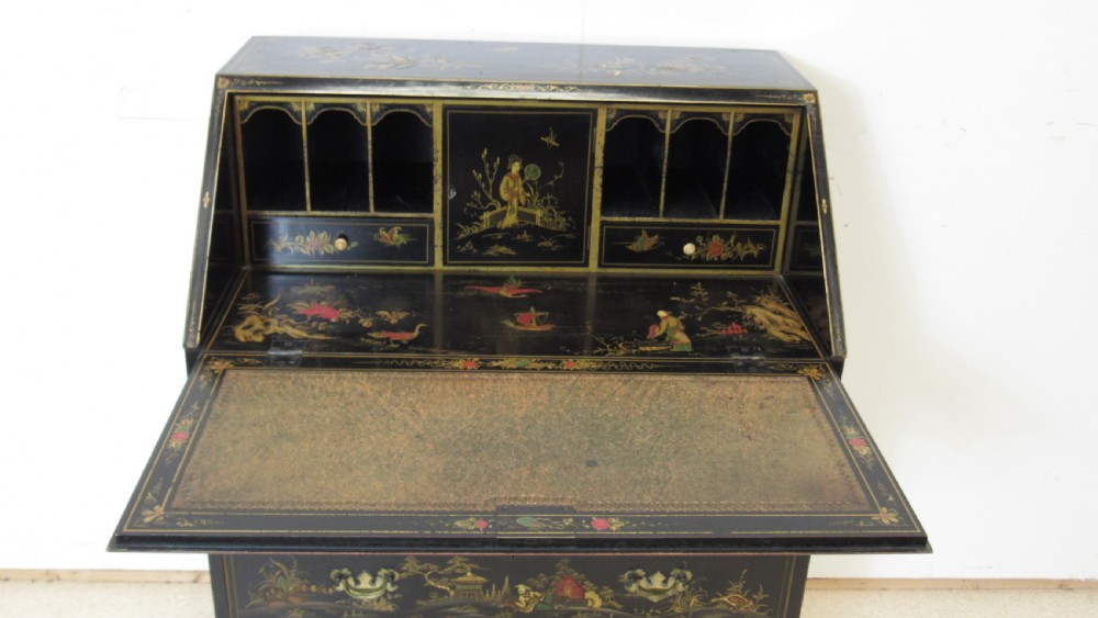 A black lacquered slant-front writing bureau decorated with detailed gold chinoiserie figurative landscapes and fitted with multiple drawers. View VI