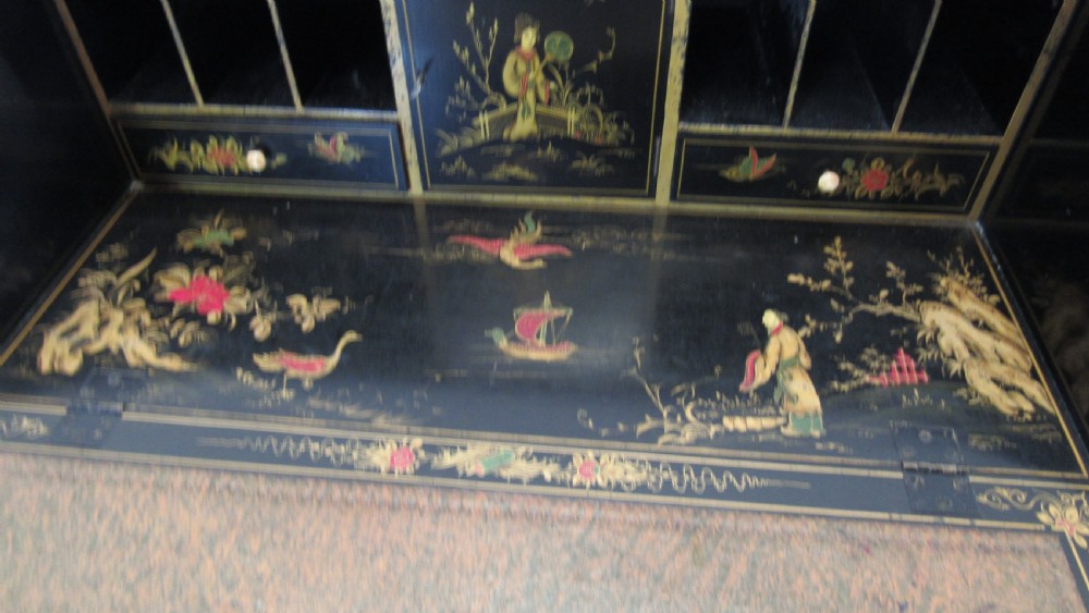 A black lacquered slant-front writing bureau decorated with detailed gold chinoiserie figurative landscapes and fitted with multiple drawers. View VIII