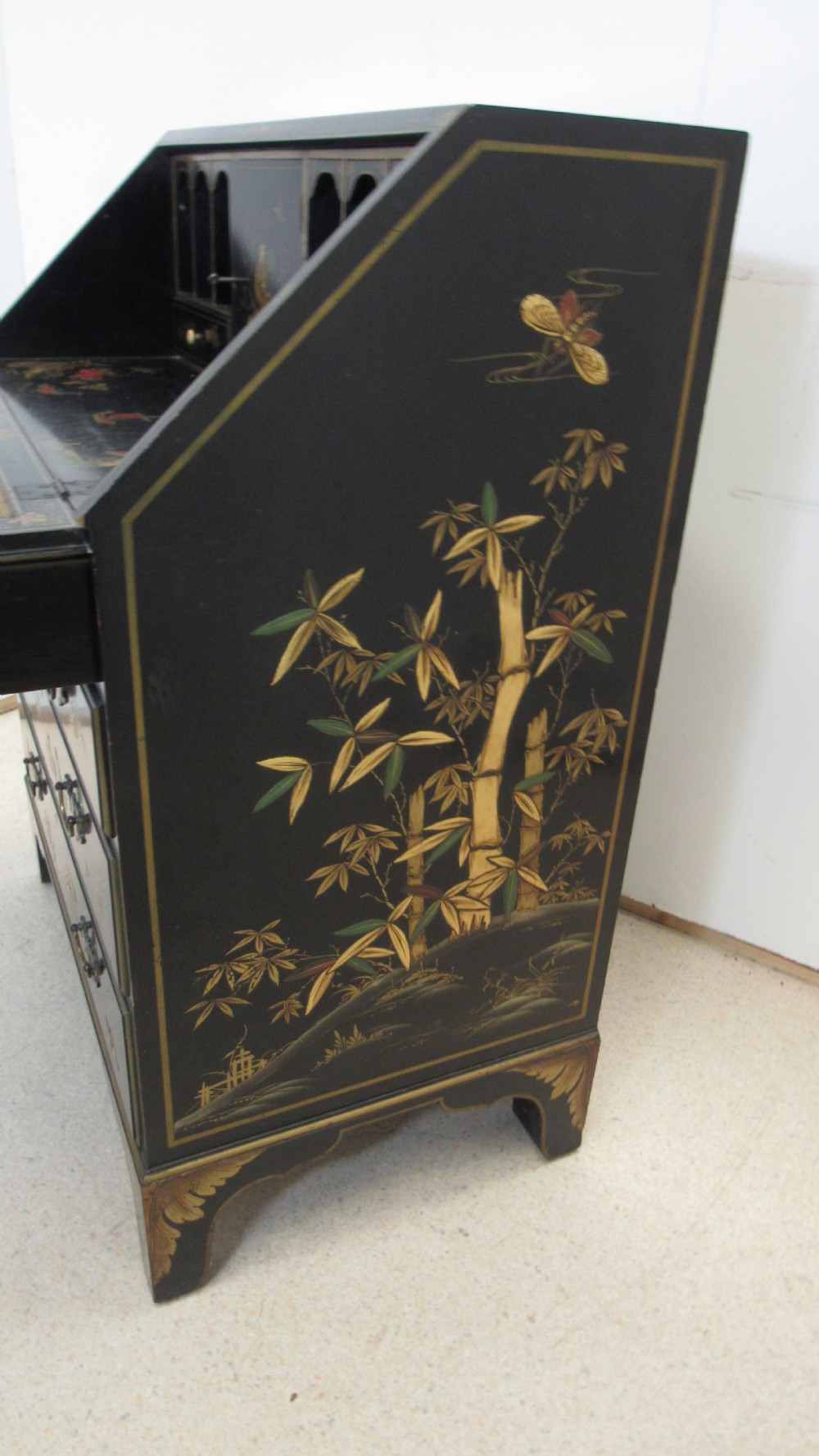 A black lacquered slant-front writing bureau decorated with detailed gold chinoiserie figurative landscapes and fitted with multiple drawers. View XI