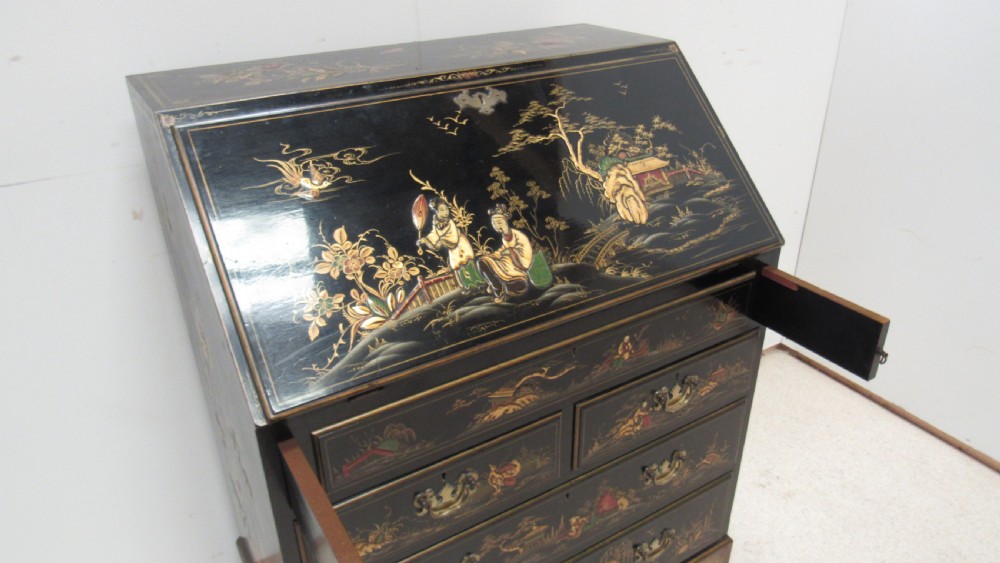 A black lacquered slant-front writing bureau decorated with detailed gold chinoiserie figurative landscapes and fitted with multiple drawers. View XIII