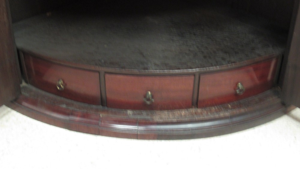 An antique Georgian bowfront corner cupboard crafted from dark mahogany with twin doors, brass H-hinges, and decorative escutcheons. View VII