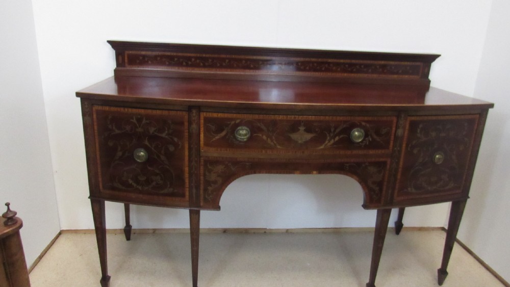 An antique mahogany sideboard with central drawer and side cupboards decorated with fine floral marquetry inlay on tapered legs. View II