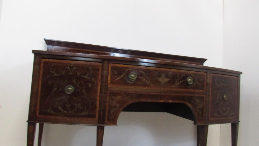 An antique mahogany sideboard with central drawer and side cupboards decorated with fine floral marquetry inlay on tapered legs. View III