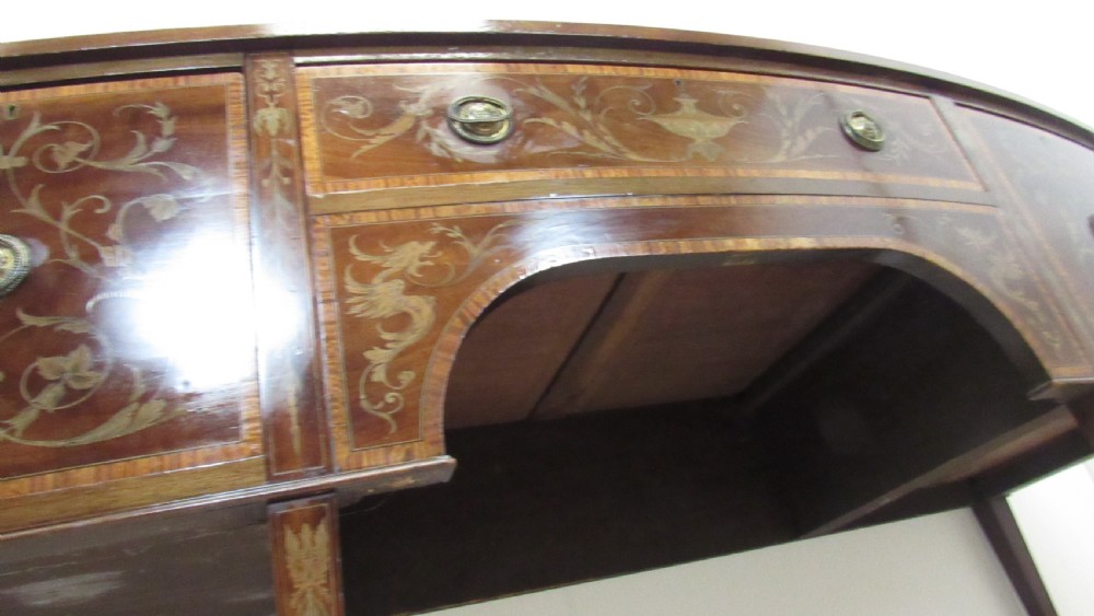 An antique mahogany sideboard with central drawer and side cupboards decorated with fine floral marquetry inlay on tapered legs. View V