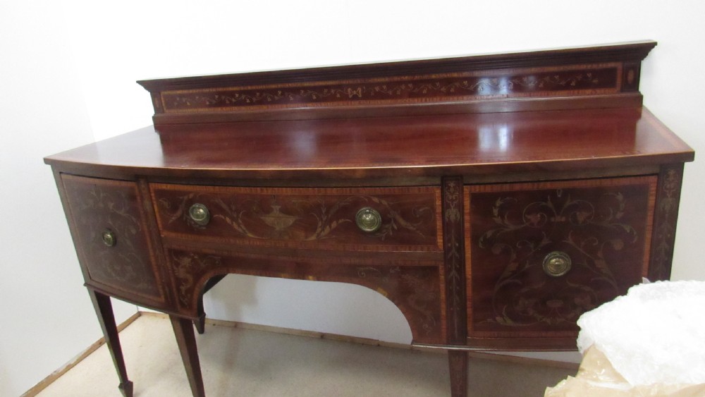 An antique mahogany sideboard with central drawer and side cupboards decorated with fine floral marquetry inlay on tapered legs. View VI