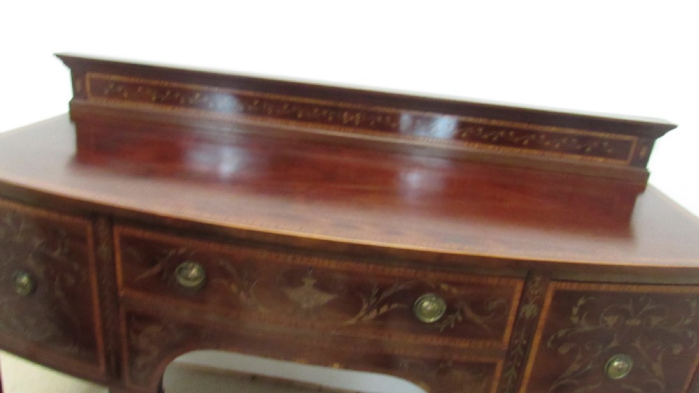 An antique mahogany sideboard with central drawer and side cupboards decorated with fine floral marquetry inlay on tapered legs. View VII