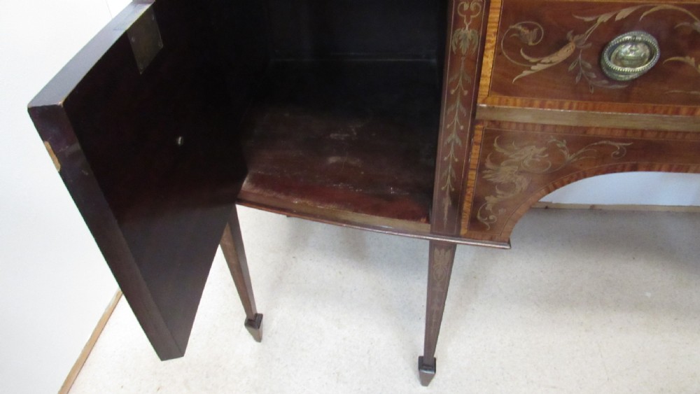 An antique mahogany sideboard with central drawer and side cupboards decorated with fine floral marquetry inlay on tapered legs. View IX