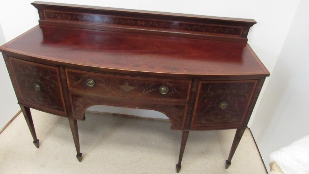 An antique mahogany sideboard with central drawer and side cupboards decorated with fine floral marquetry inlay on tapered legs. View XII