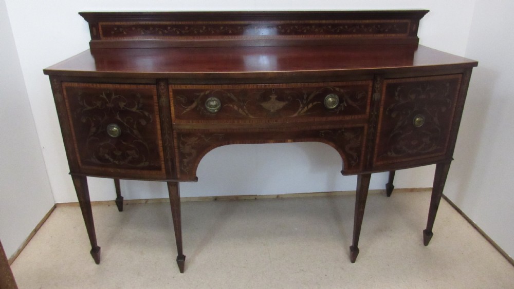An antique mahogany sideboard with central drawer and side cupboards decorated with fine floral marquetry inlay on tapered legs. View XIII