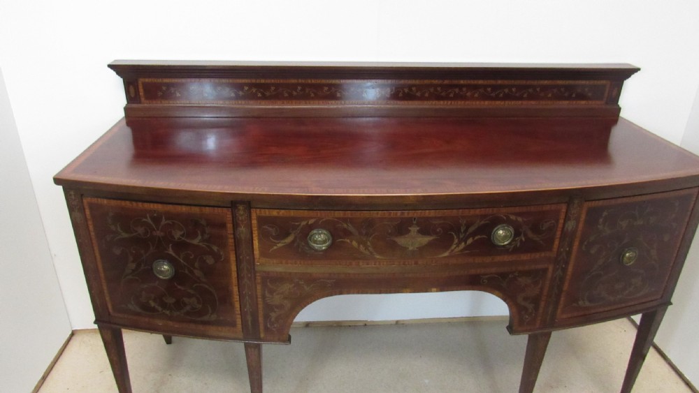 An antique mahogany sideboard with central drawer and side cupboards decorated with fine floral marquetry inlay on tapered legs. View XIV
