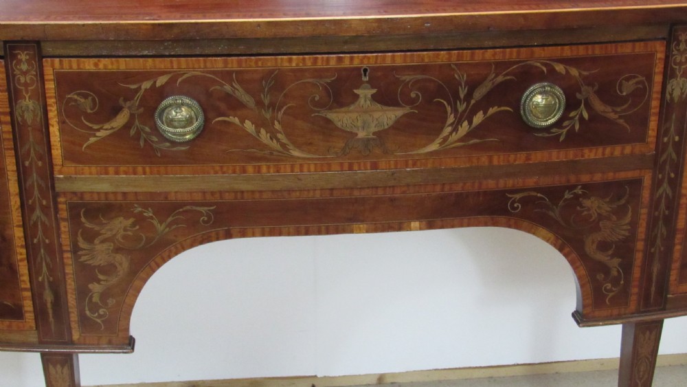 An antique mahogany sideboard with central drawer and side cupboards decorated with fine floral marquetry inlay on tapered legs. View XV