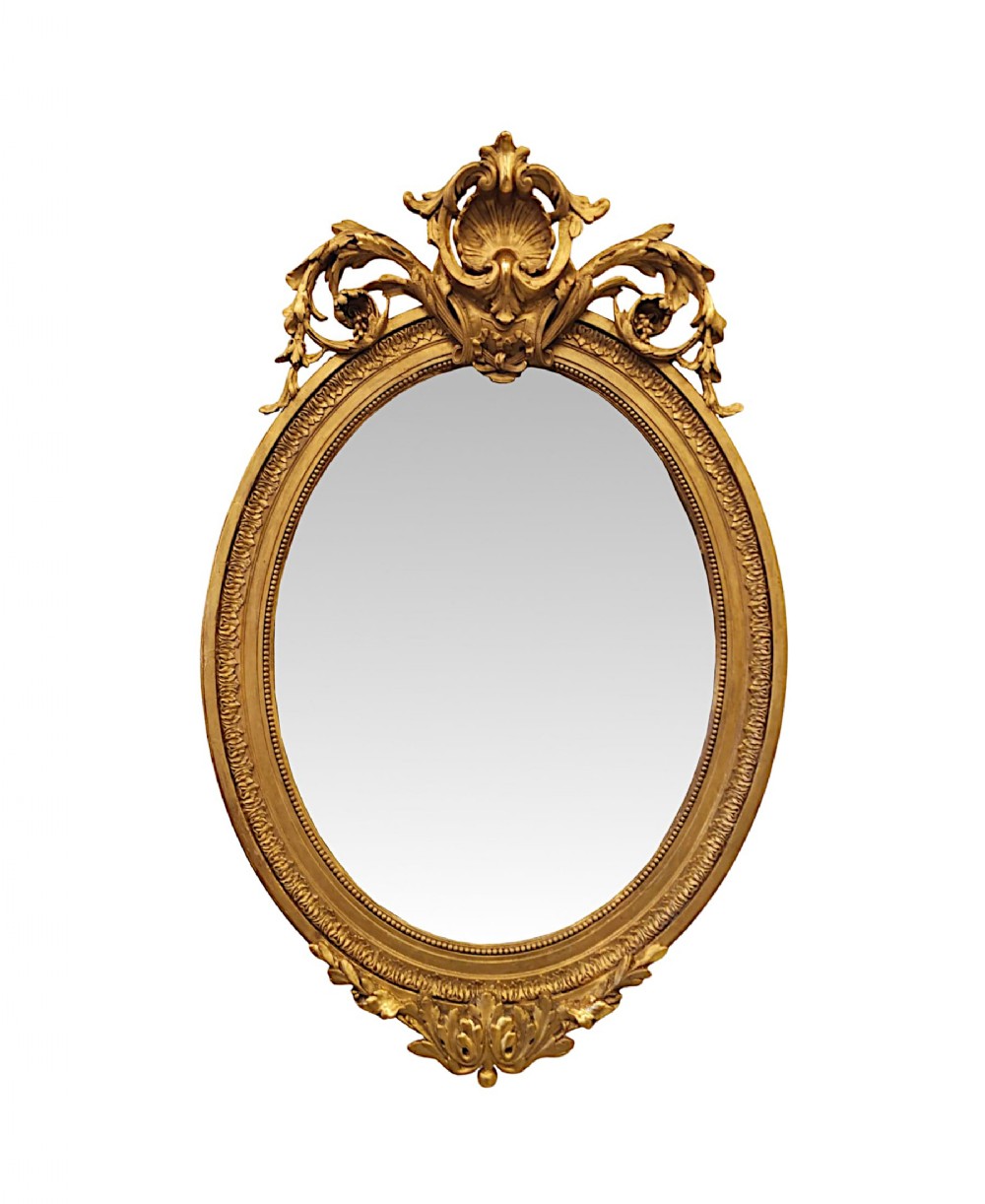 A 19th-century oval giltwood mirror featuring an elaborate shell crest and carved leaf mouldings.