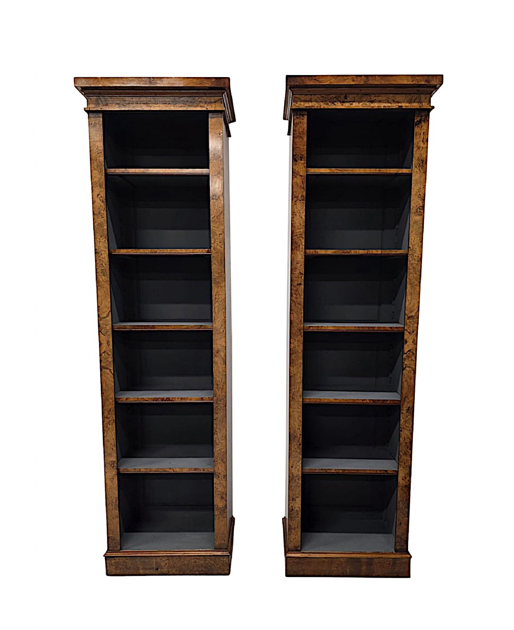 A matching pair of tall, slim burr walnut open bookshelves featuring moulded upper cornices and solid plinth bases.
