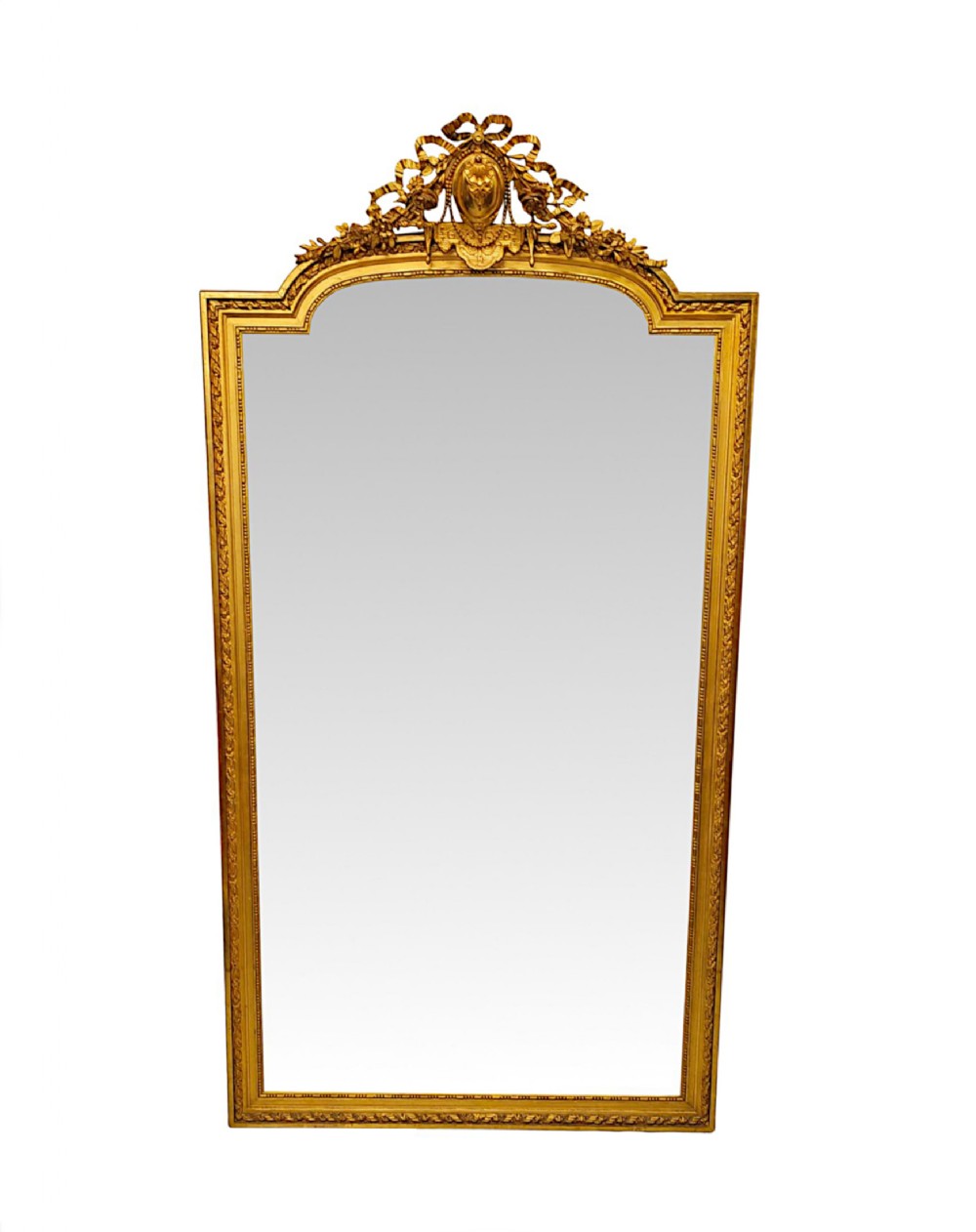 A tall 19th-century rectangular giltwood mirror featuring an ornate bow crest with floral garlands and a bevelled glass plate.