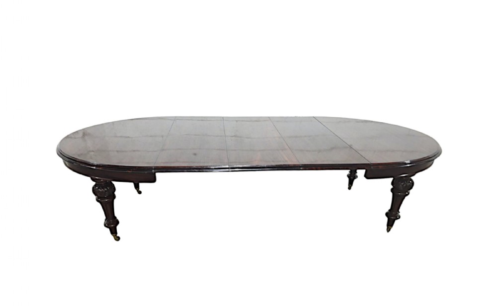 A restored 19th-century dark mahogany extending D-end dining table supported by turned and carved legs with brass castors.