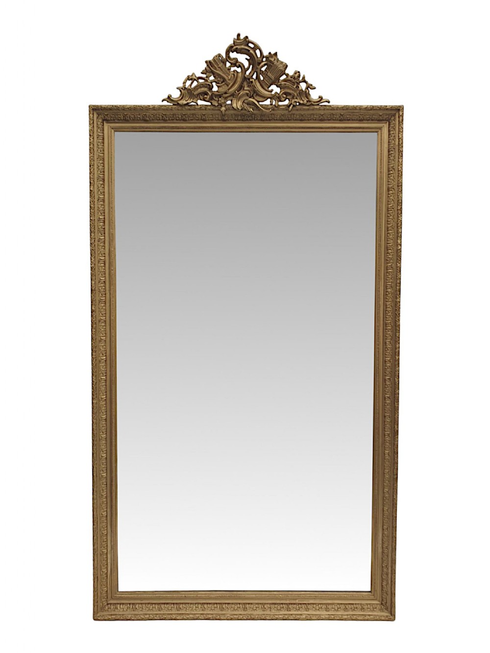A tall rectangular 19th-century mirror in a gilded frame topped with an intricate ornate crest.