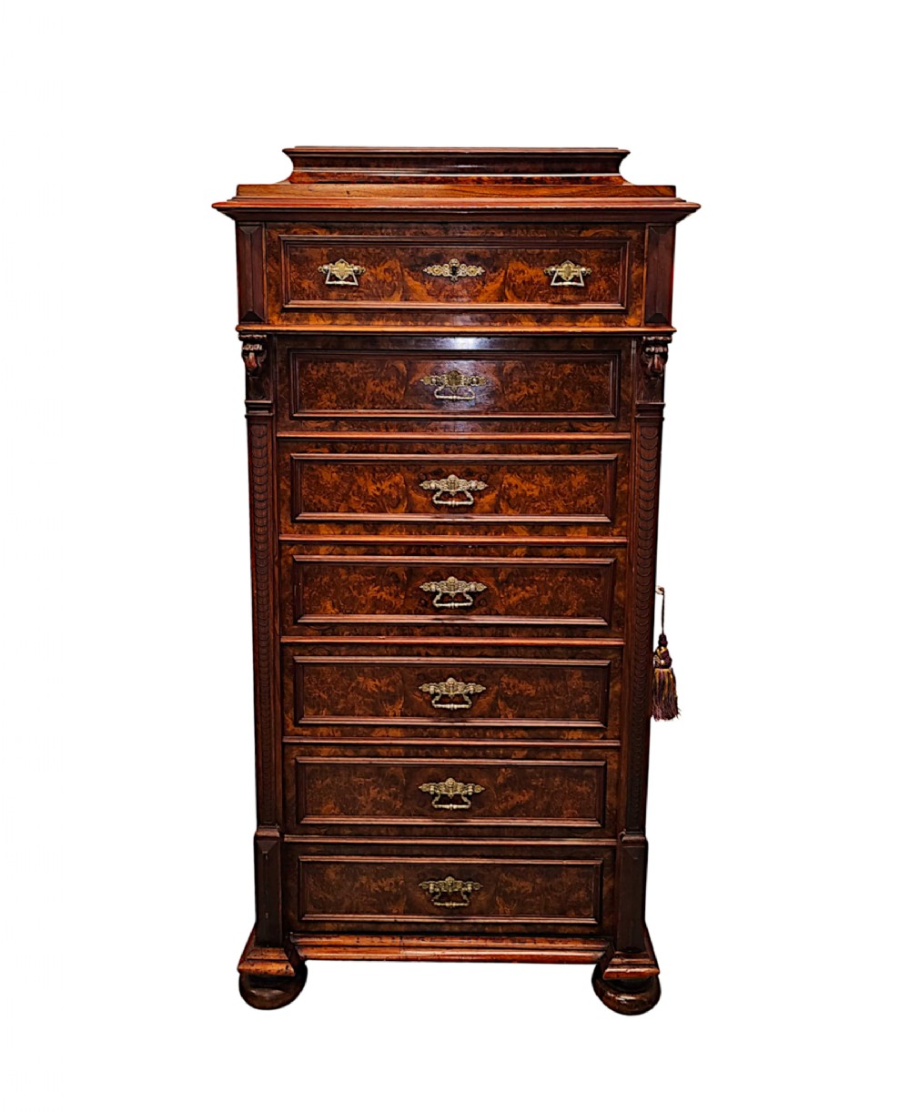 A tall 19th-century burr walnut Wellington chest featuring seven stacked drawers with brass handles and a hinged side locking bar.