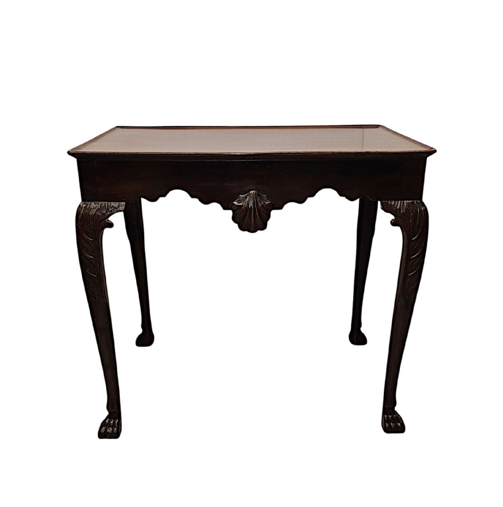 A dark mahogany silver table featuring carved cabriole legs with claw and ball feet, a dished tray top, and a carved scallop shell motif on the apron.