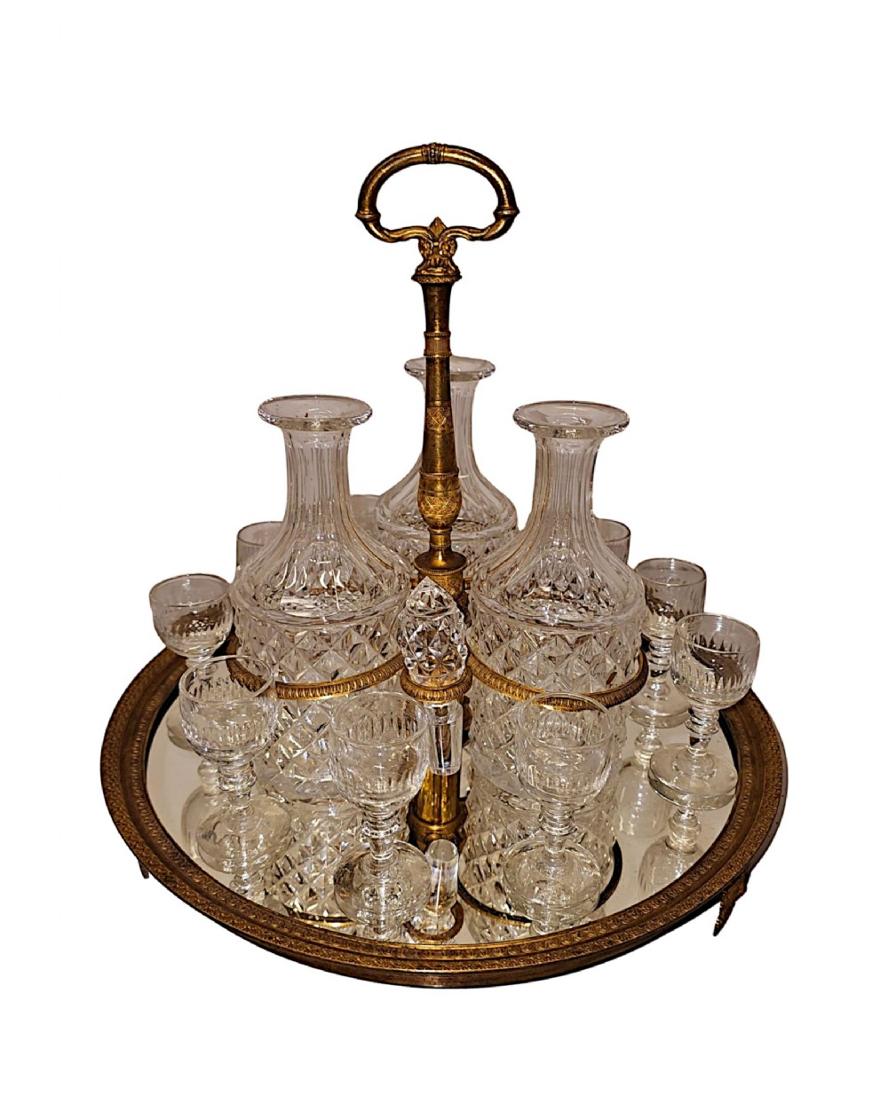A 19th-century French circular ormolu tantalus set featuring four cut glass decanters and matching glasses on a mirrored base with a central gilt handle.