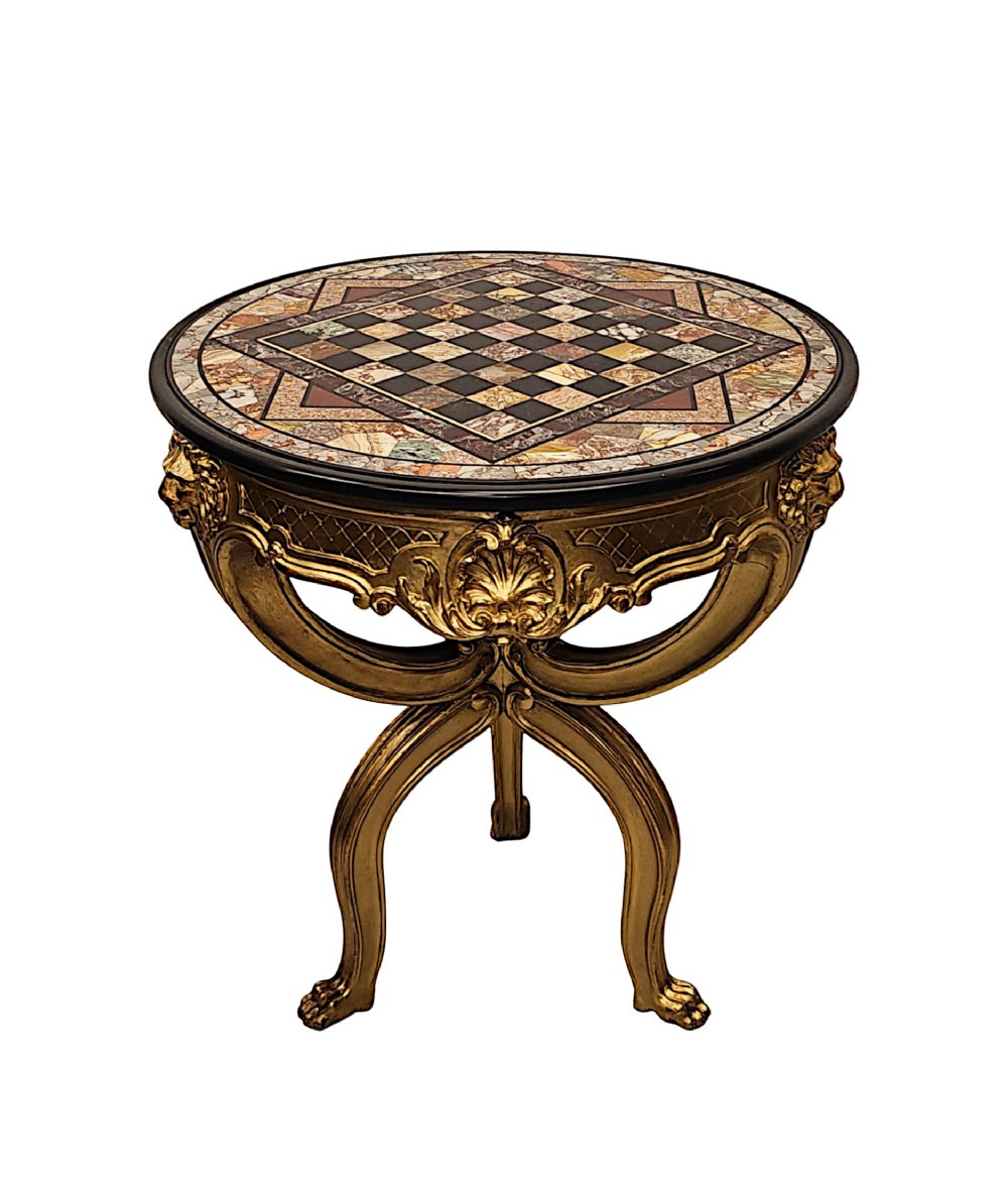 A circular nineteenth-century games table featuring an inlaid specimen marble chessboard top supported on a carved giltwood tripod base with lion masks and paw feet.