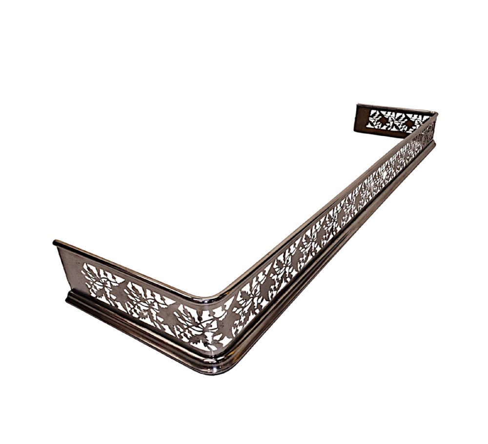 A nineteenth-century polished steel fireplace fender featuring intricate pierced foliate fretwork across the front and side return sections.