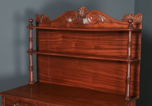 fig 6. A Regency mahogany two-door chiffonier cabinet featuring tiered upper display shelves, carved scroll cresting, and turned legs.