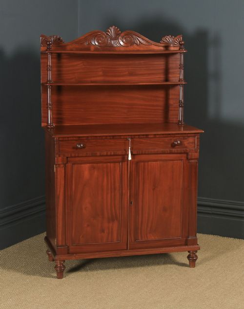 fig 1. A Regency mahogany two-door chiffonier cabinet featuring tiered upper display shelves, carved scroll cresting, and turned legs.