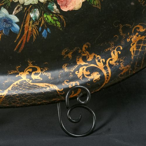 fig 2. An oval ebonised papier-mache serving tray featuring a hand-painted floral bouquet centrepiece surrounded by gilt scrollwork detailing along the rim.