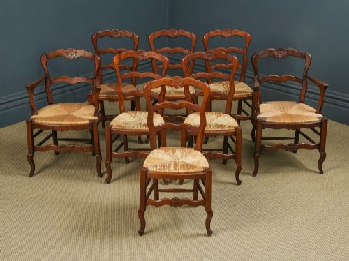 fig 1. A set of eight French provincial oak dining chairs featuring wavy ladder backrests, hand-woven rush seats, and carved cabriole legs.