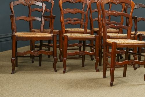 fig 4. A set of eight French provincial oak dining chairs featuring wavy ladder backrests, hand-woven rush seats, and carved cabriole legs.