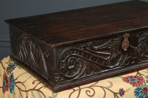 fig 2. A dark brown 17th-century carved oak bible box featuring intricate scrollwork on the front panel and a central iron keyhole escutcheon.