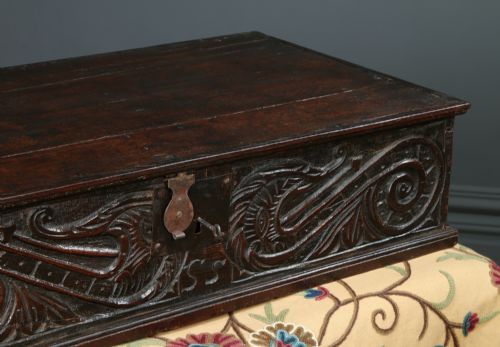 fig 5. A dark brown 17th-century carved oak bible box featuring intricate scrollwork on the front panel and a central iron keyhole escutcheon.