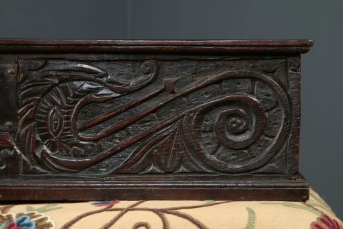 fig 6. A dark brown 17th-century carved oak bible box featuring intricate scrollwork on the front panel and a central iron keyhole escutcheon.
