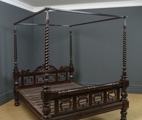 fig 3. A dark brown Anglo-Indian colonial four poster bed with spiral turned posts and a carved wooden footboard.
