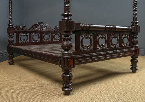 fig 4. A dark brown Anglo-Indian colonial four poster bed with spiral turned posts and a carved wooden footboard.