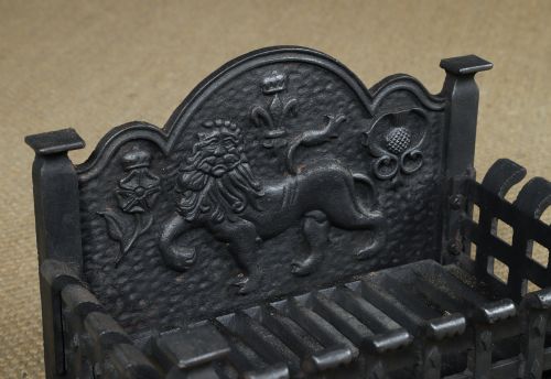 fig 4. A black cast iron fire grate featuring a relief-carved heraldic lion backplate and portcullis lattice front basket.