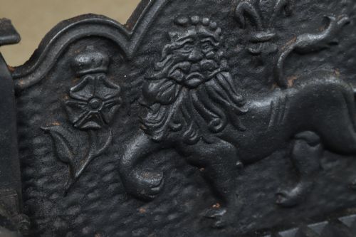 fig 5. A black cast iron fire grate featuring a relief-carved heraldic lion backplate and portcullis lattice front basket.