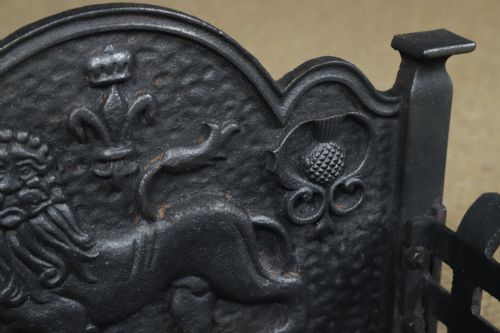 fig 6. A black cast iron fire grate featuring a relief-carved heraldic lion backplate and portcullis lattice front basket.
