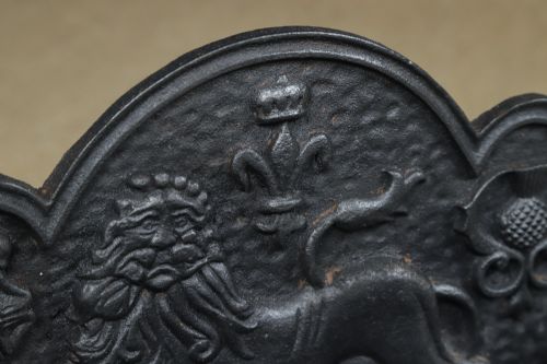 fig 7. A black cast iron fire grate featuring a relief-carved heraldic lion backplate and portcullis lattice front basket.