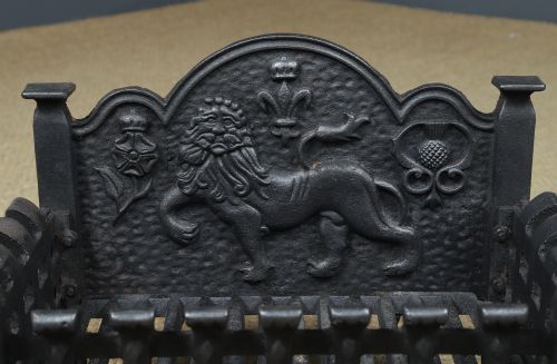 fig 8. A black cast iron fire grate featuring a relief-carved heraldic lion backplate and portcullis lattice front basket.