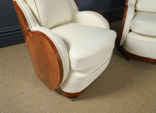 fig 2. An antique Art Deco three-piece lounge suite consisting of a three-seater sofa and two matching armchairs upholstered in cream leather with curved walnut side panels.
