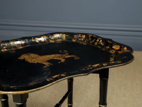 fig 3. An ebonised Victorian papier-mache tray table featuring gilt Chinoiserie decoration and a lion motif, resting on a faux-bamboo base.