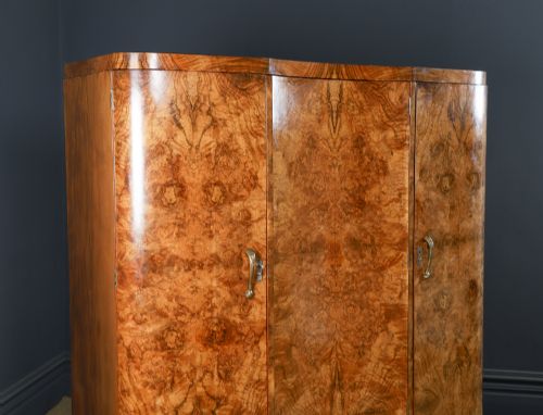 fig 1. An English Art Deco triple-door wardrobe crafted from figured burr walnut with curved sides and vertical handles.