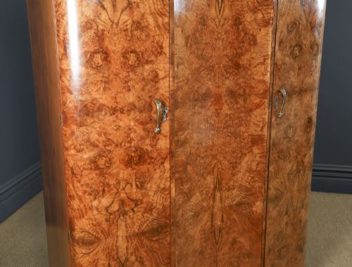 fig 2. An English Art Deco triple-door wardrobe crafted from figured burr walnut with curved sides and vertical handles.