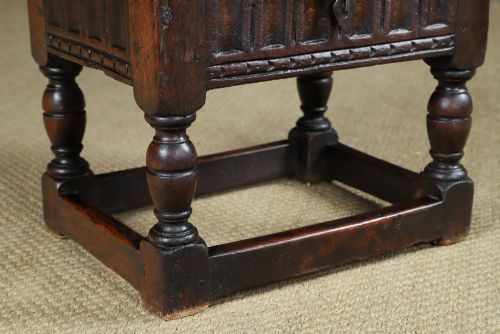 fig 3. A small antique dark oak box stool featuring a hinged top lid, hand-carved frieze panels, turned legs, and square perimeter stretchers.