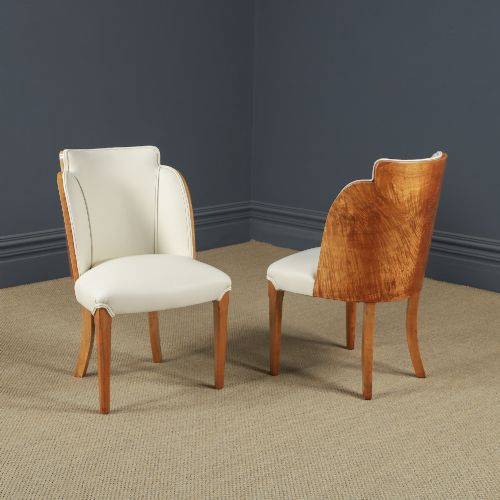 fig 7. An English Art Deco dining suite featuring a rectangular satinwood and maple dining table with a glass top and six cream leather upholstered chairs with curved veneered backs.