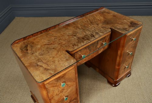fig 5. An Art Deco burr walnut pedestal writing desk with green circular knobs and a fitted glass top.