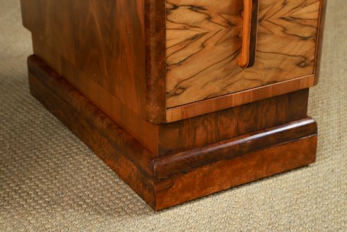 fig 5. An Art Deco walnut and burr elm pedestal desk featuring stepped side pedestals, bookmatched wood veneers, wooden handles, and a fitted glass top.