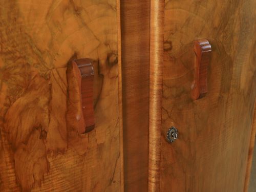 fig 2. An Art Deco walnut two door wardrobe featuring a bow front design, carved wood handles, and figured timber grain.