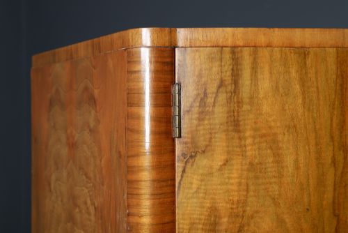 fig 4. An Art Deco walnut two door wardrobe featuring a bow front design, carved wood handles, and figured timber grain.